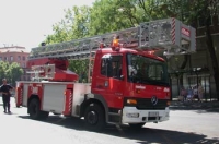 Camión de bomberos color rojo con sirenas y escaleras.